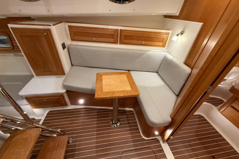 Slide: The Image of 2026 Back Cove 39O yacht interior with wooden cabinetry, cushioned seating, and compact table. - 32