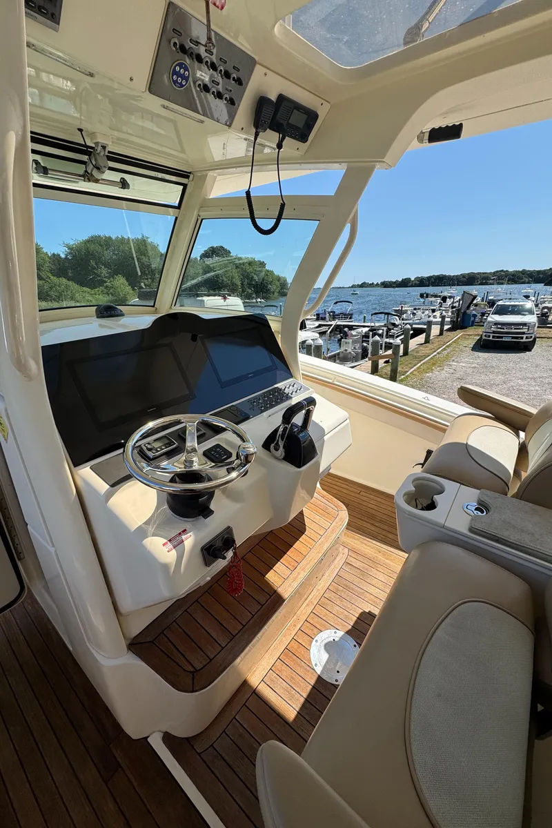 Slide: The Image of Helm of 2011 Scout 345 XSF boat with modern controls and scenic marina view. - 15