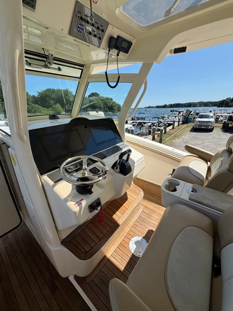 Slide: The Image of 2011 Scout 345 XSF boat interior with steering wheel, dashboard, and seating, dockside view. - 16