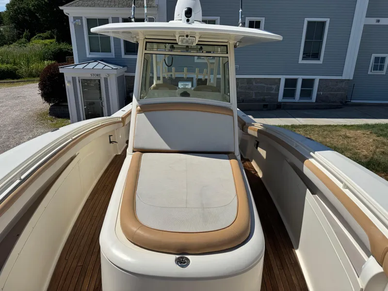 Slide: The Image of 2011 Scout 345 XSF boat with cushioned seating and sleek design, docked near a building. - 27