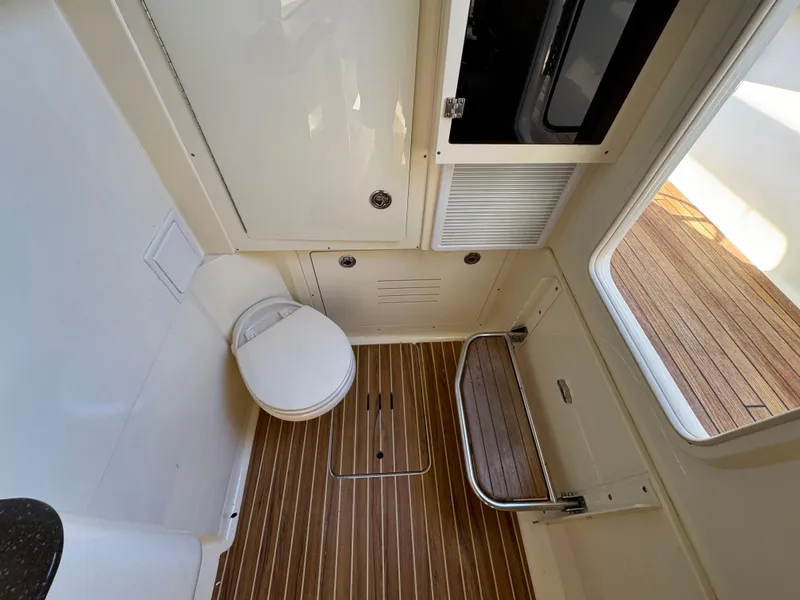 Slide: The Image of 2011 Scout 345 XSF boat interior with wooden flooring and compact bathroom amenities. - 31