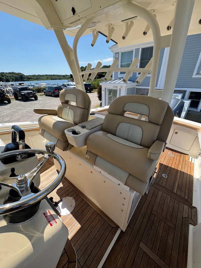 Slide: The Image of 2011 Scout 345 XSF boat interior with dual helm seats and wooden deck. - 32