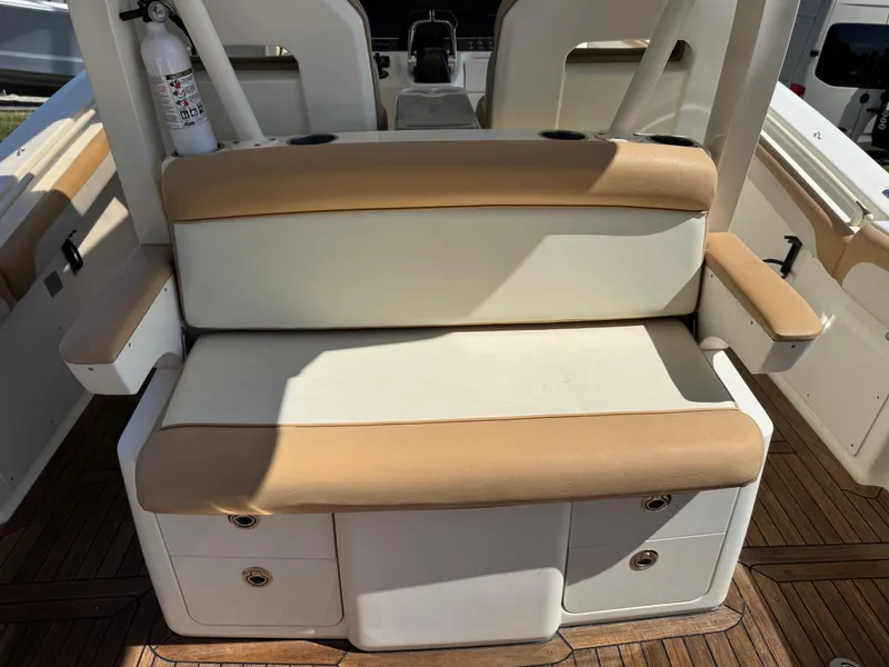 Slide: The Image of 2011 Scout 345 XSF boat seating area with tan and white cushions, wooden deck, and fire extinguisher. - 37