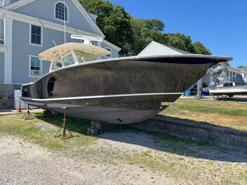 Slide: The Image of 2011 Scout 345 XSF boat on dry land, near a large building, under clear blue sky. - 4