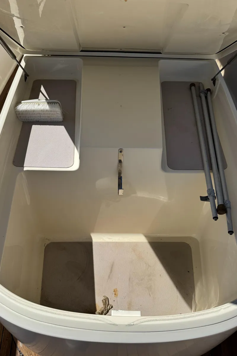 Slide: The Image of Open storage compartment on 2011 Scout 345 XSF boat with cleaning supplies and rods. - 46