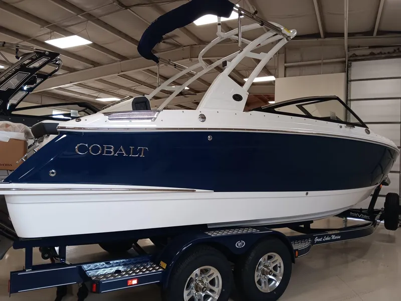 Slide: The Image of 2026 Cobalt R4 boat in showroom, blue and white design, on trailer. - 2
