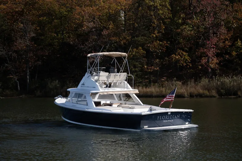 Slide: The Image of 1969 Bertram 31 Classic boat on a serene lake with autumn foliage. - 1