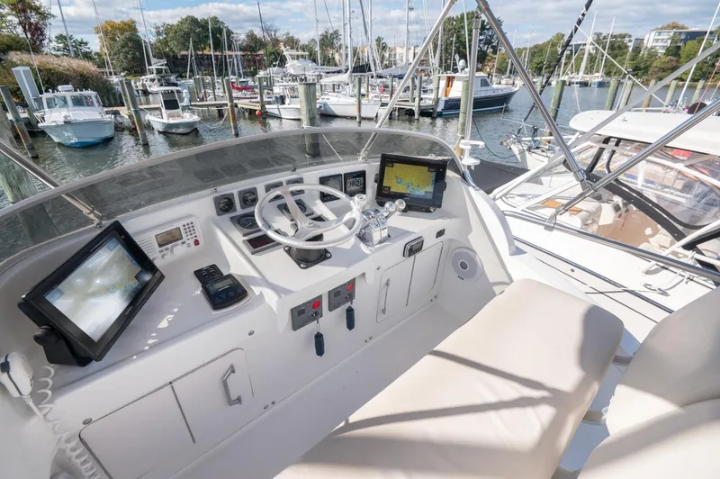 Slide: The Image of 1969 Bertram 31 Classic boat deck with four wooden chairs, docked at a marina. - 17