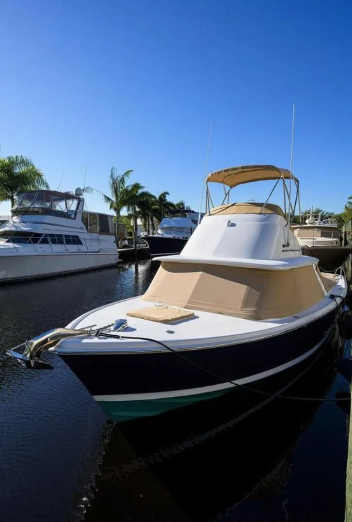 Slide: The Image of 1969 Bertram 31 Classic yacht docked in a marina under clear blue skies. - 31