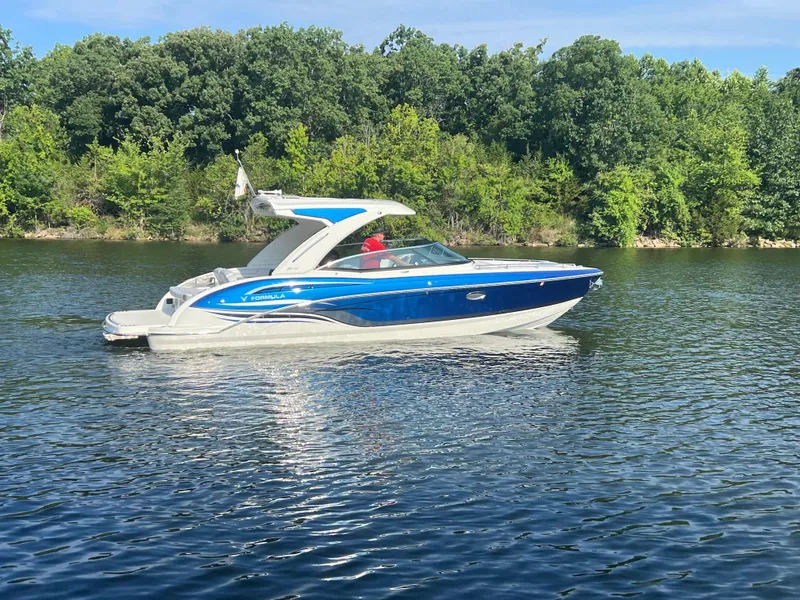 Slide: The Image of 2023 Formula 310 Bowrider I/O cruising on a serene lake with lush green trees. - 21
