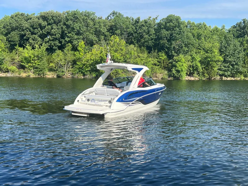 Slide: The Image of 2023 Formula 310 Bowrider I/O cruising on a serene lake with lush green trees. - 22