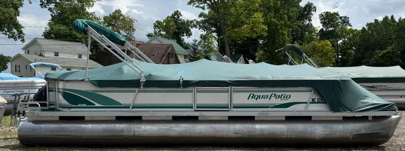 The Image of 1999 AquaPatio 270fe pontoon boat with green cover, parked outdoors. - 0