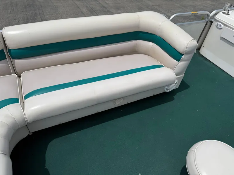 Slide: The Image of 1999 AquaPatio 270fe boat interior with white and teal seating on green flooring. - 11