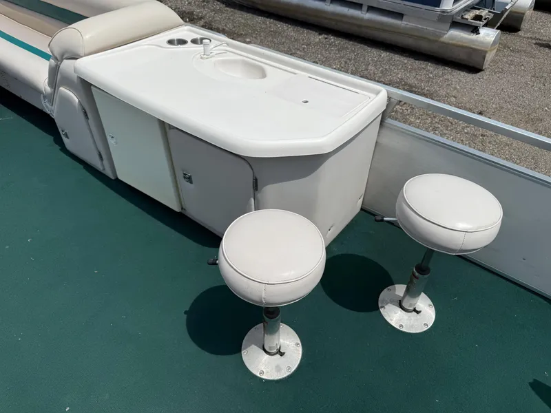 Slide: The Image of 1999 AquaPatio 270fe boat interior with sink and two stools on green carpet. - 12