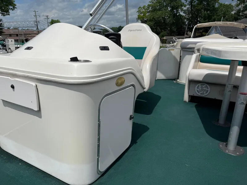 Slide: The Image of 1999 AquaPatio 270fe boat interior with white seating and green flooring. - 16