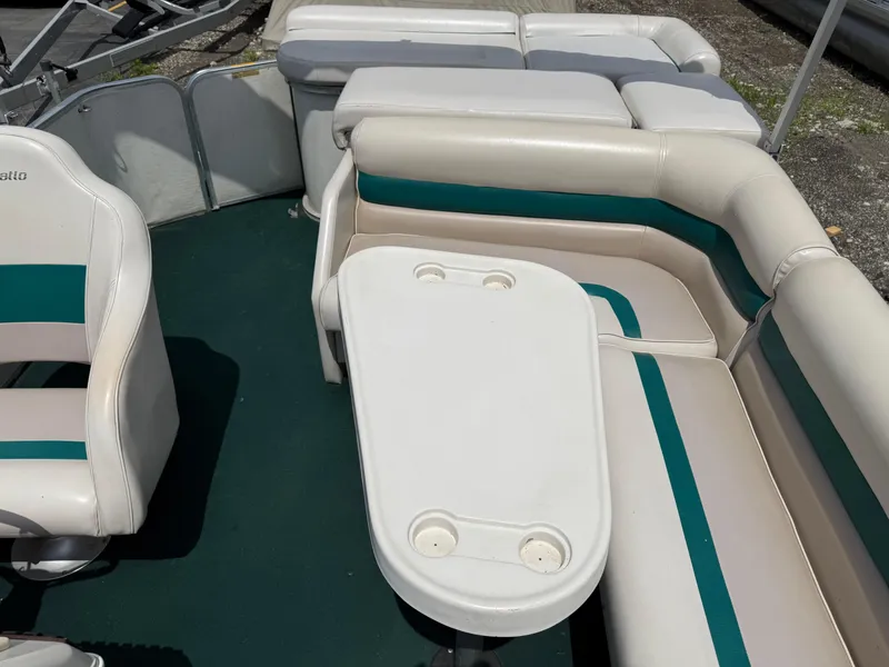 Slide: The Image of Interior of a 1999 AquaPatio 270fe boat with white and teal seating. - 17