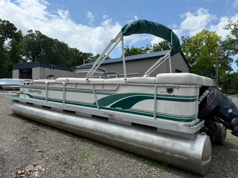 Slide: The Image of 1999 AquaPatio 270fe pontoon boat with green accents, parked outdoors. - 2