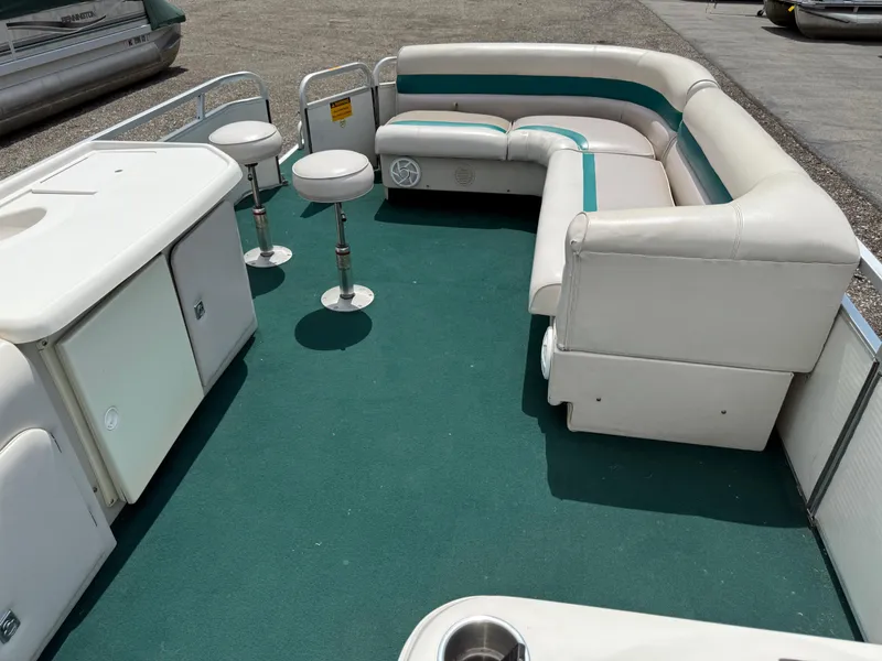 Slide: The Image of 1999 AquaPatio 270fe pontoon boat interior with green carpet and white seating. - 24