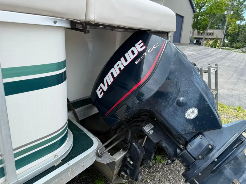Slide: The Image of 1999 AquaPatio 270fe boat with Evinrude E-TEC outboard motor, parked on gravel. - 3