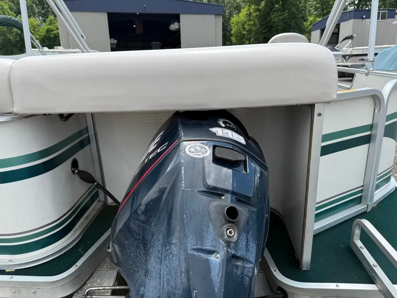 Slide: The Image of 1999 AquaPatio 270fe boat with outboard motor, docked near a storage facility. - 4