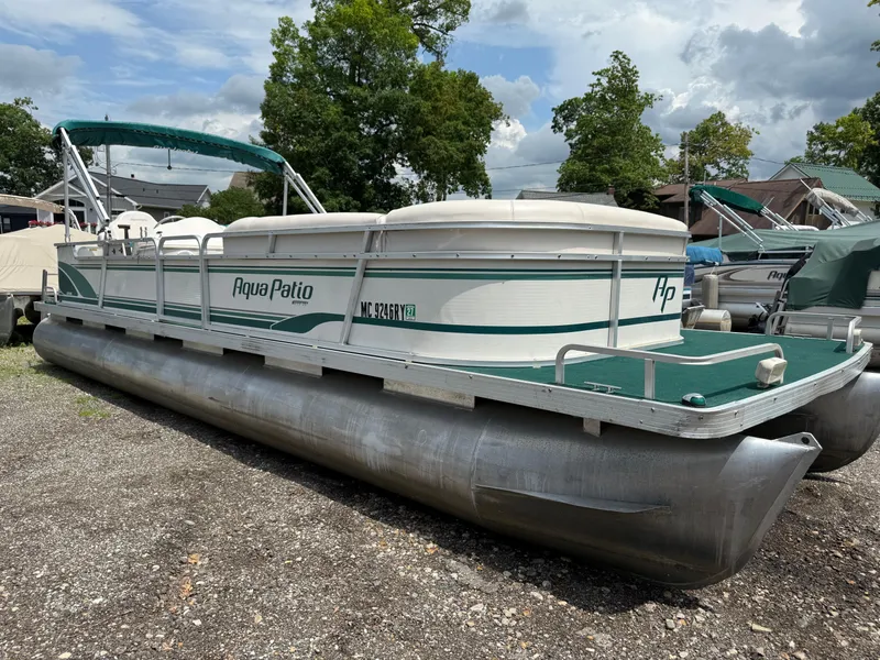 Slide: The Image of 1999 AquaPatio 270fe pontoon boat with green canopy, parked on gravel. - 5