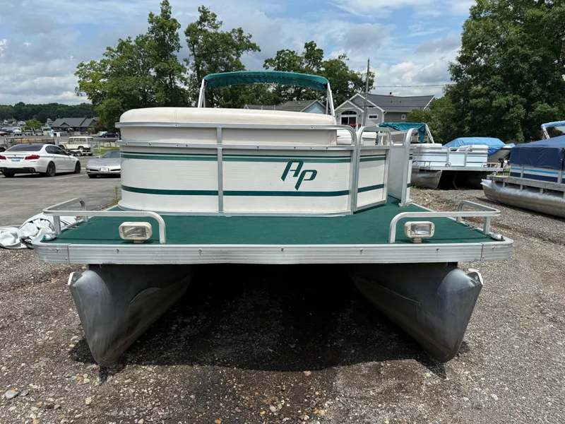 Slide: The Image of 1999 AquaPatio 270fe pontoon boat on gravel lot, surrounded by trees and vehicles. - 6