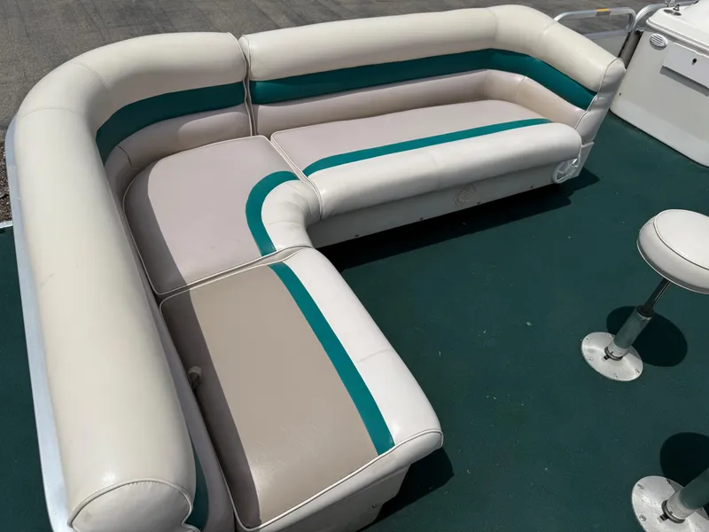 Slide: The Image of 1999 AquaPatio 270fe boat interior with white and teal seating on green carpet. - 9