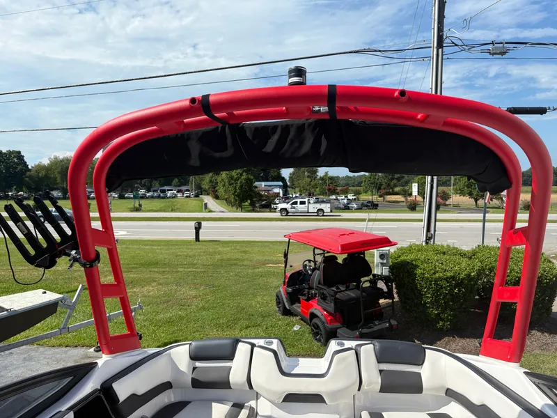 Slide: The Image of 2019 Yamaha Boats AR195 with red wakeboard tower, parked near a road and golf cart. - 13