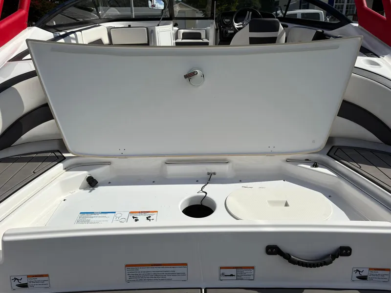 Slide: The Image of 2019 Yamaha AR195 boat interior storage compartment open, showcasing seating and dashboard. - 15