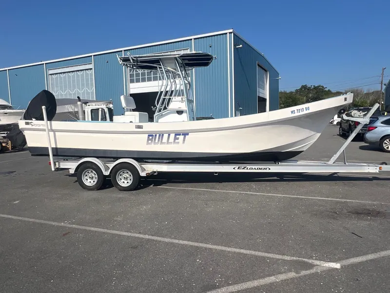 Slide: The Image of 2023 Banks Panga 26 Panga boat on trailer, parked in a lot near a blue building. - 0