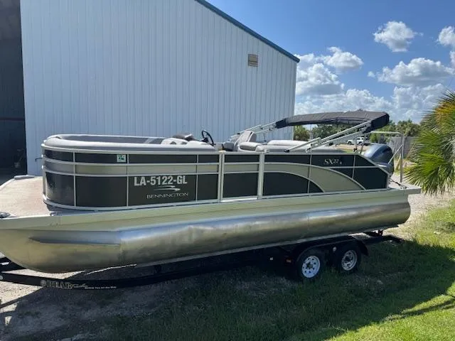 Slide: The Image of 2020 Bennington SX22 pontoon boat on trailer, parked outdoors near a building. - 3