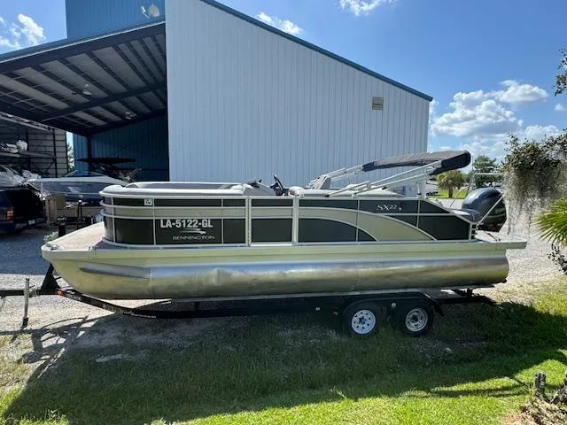 Slide: The Image of 2020 Bennington SX22 pontoon boat on trailer, parked near a large storage building. - 4