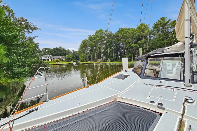 Slide: The Image of 2018 Maine Cat 38 LS catamaran docked by a serene, tree-lined waterfront. - 15