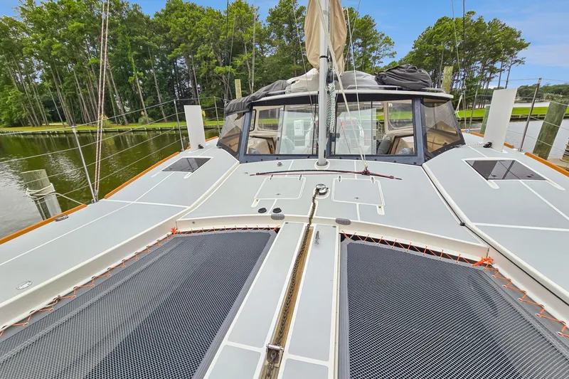 Slide: The Image of 2018 Maine Cat 38 LS catamaran deck with netting, docked near lush trees. - 24