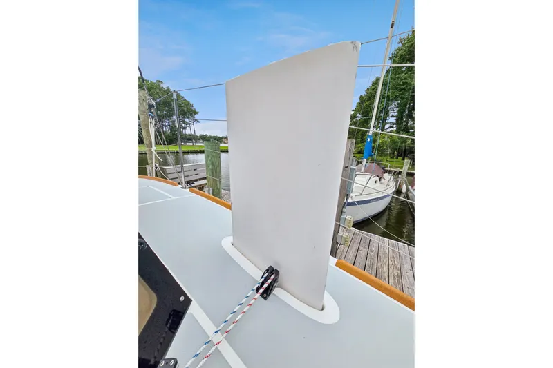 Slide: The Image of 2018 Maine Cat 38 LS sailboat deck with centerboard and rigging, docked near trees. - 31