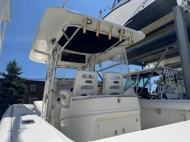Slide: The Image of 2004 Boston Whaler 320 Outrage boat with dual seats and canopy, docked outdoors. - 7