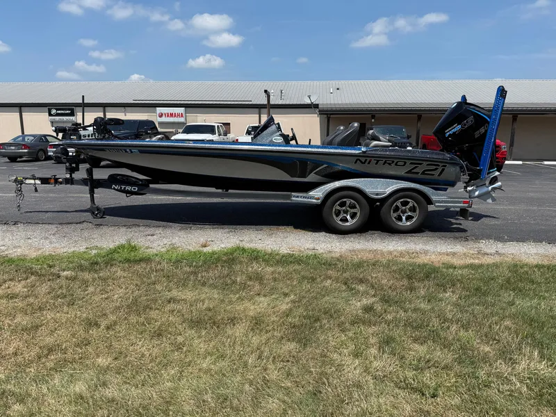 Slide: The Image of 2019 Nitro Z21 boat on trailer, parked outdoors near dealership, under clear blue sky. - 4