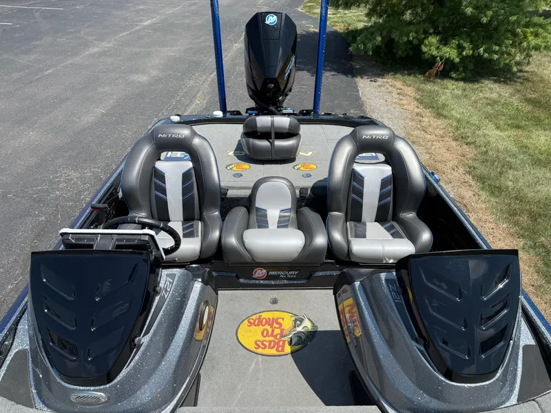 Slide: The Image of 2019 Nitro Z21 boat interior with three seats and Mercury engine, parked on pavement. - 7
