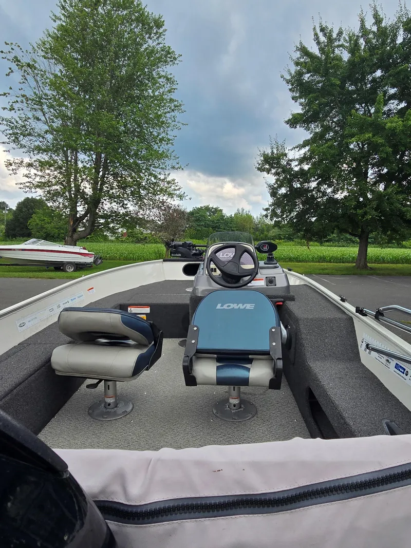 Slide: The Image of 2012 Lowe AN160S boat interior with steering wheel, seats, and lush green background. - 3