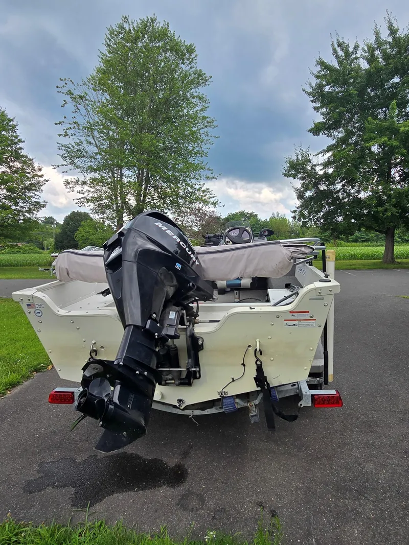 Slide: The Image of 2012 Lowe AN160S boat with outboard motor on trailer, parked on a paved road. - 6