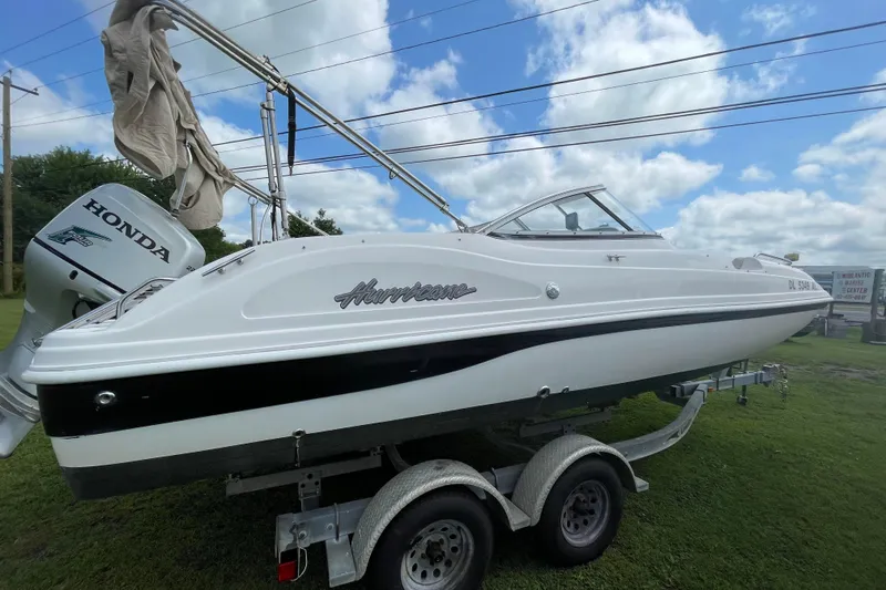 Slide: The Image of 2004 Hurricane 217 OB boat on trailer, featuring Honda outboard motor, under blue sky. - 19