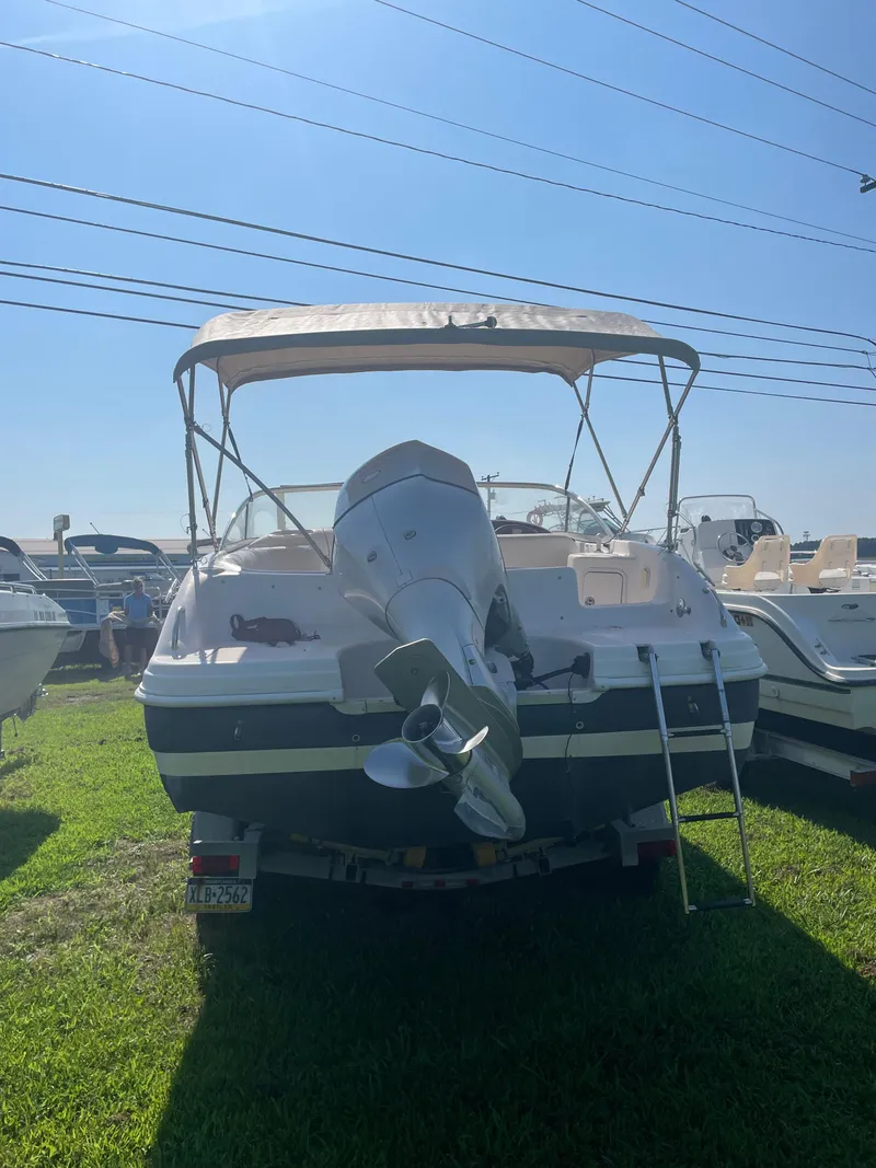 Slide: The Image of 2004 Hurricane 217 OB boat with canopy and outboard motor on grassy lot. - 2