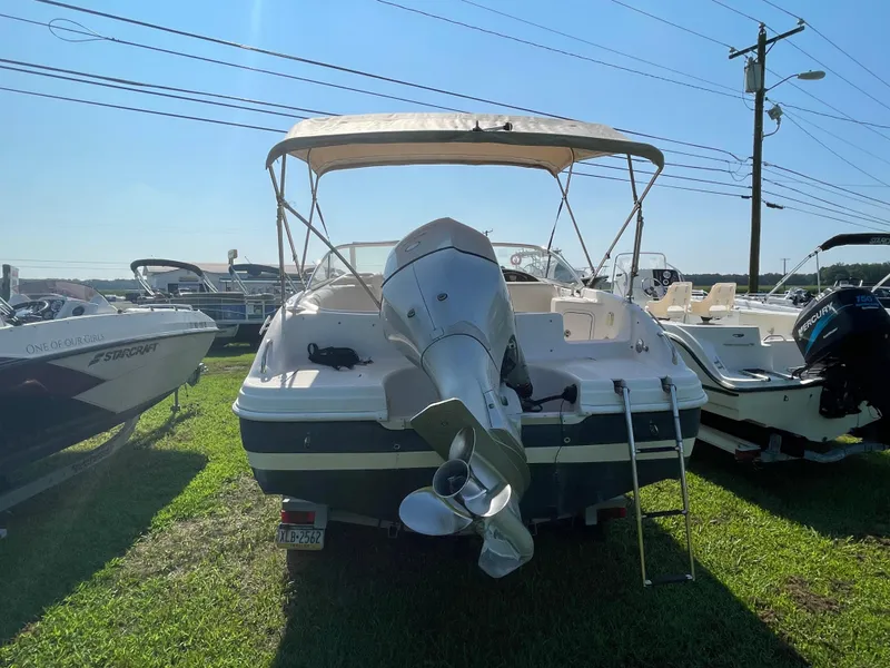 Slide: The Image of 2004 Hurricane 217 OB boat with outboard motor and canopy, parked on grass. - 8