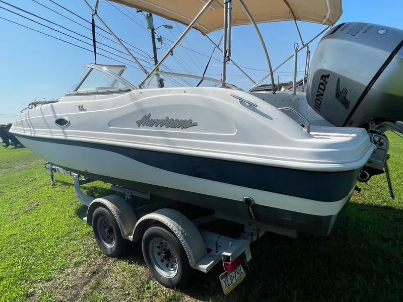 Slide: The Image of 2004 Hurricane 217 OB boat on trailer with Honda outboard motor, parked on grass. - 9