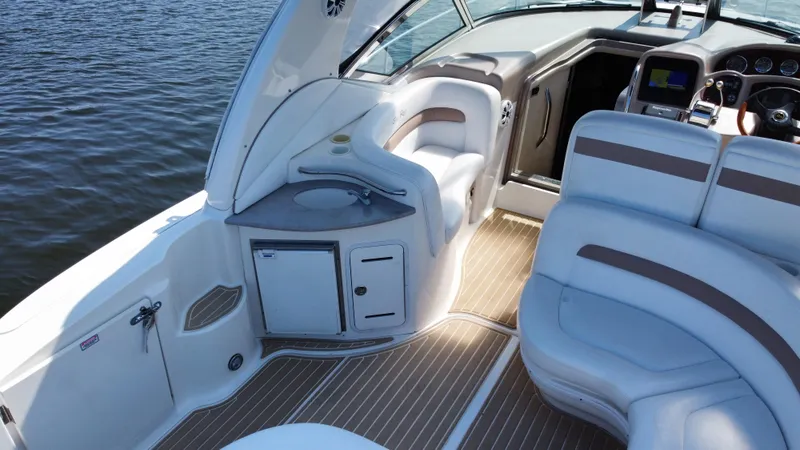 Slide: The Image of 2004 Sea Ray 320 Sundancer boat interior with seating and helm, on calm water. - 11