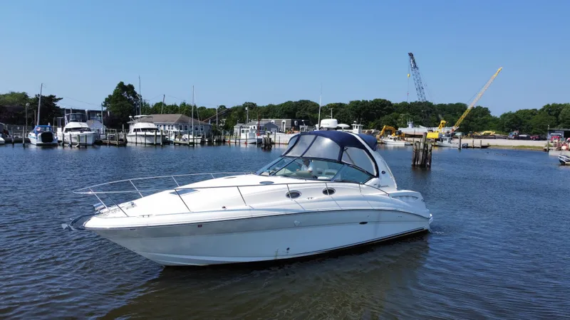 Slide: The Image of 2004 Sea Ray 320 Sundancer yacht docked in a marina under clear blue skies. - 2