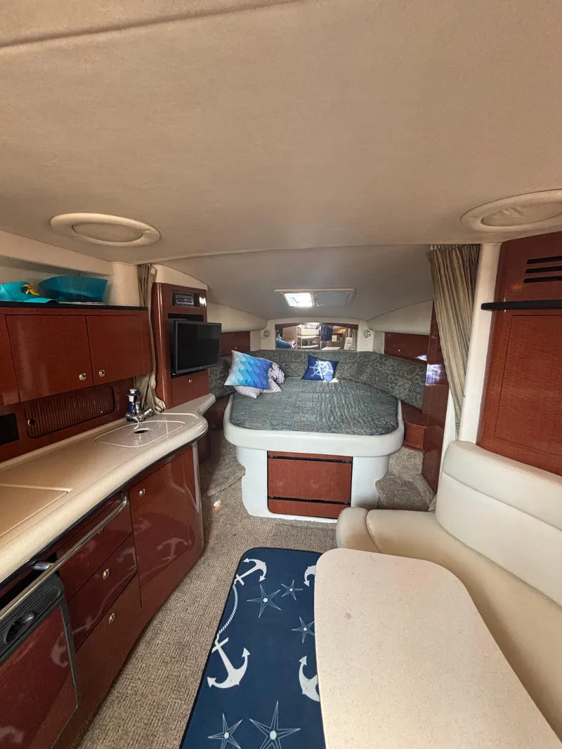 Slide: The Image of 2004 Sea Ray 320 Sundancer cabin interior with bed, kitchenette, and seating area. - 33