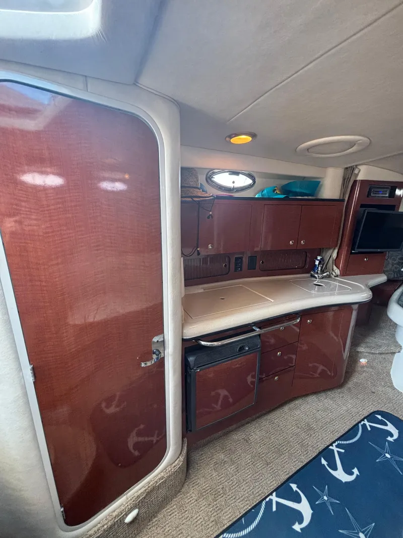 Slide: The Image of 2004 Sea Ray 320 Sundancer cabin interior with kitchenette and wooden cabinetry. - 34