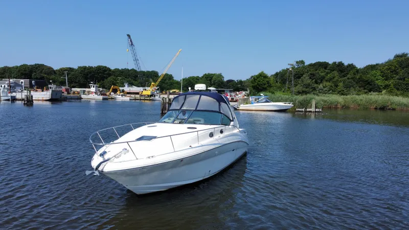 Slide: The Image of 2004 Sea Ray 320 Sundancer yacht on calm water near a marina. - 4