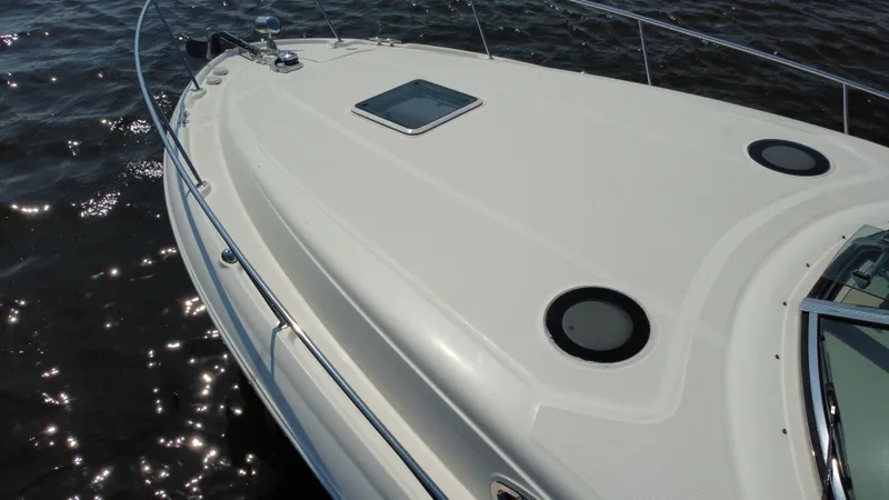 Slide: The Image of 2004 Sea Ray 320 Sundancer boat deck on water, showcasing sleek design and portholes. - 42
